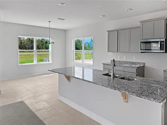 a kitchen with granite countertop a stove a sink and a microwave