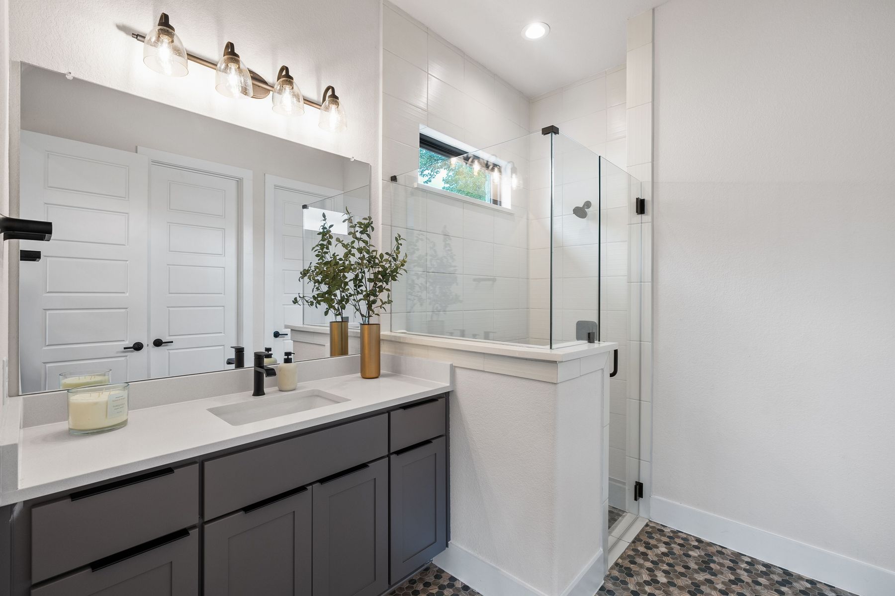 1106 Flint Ridge Trail Georgetown, TX 78628 - Photo 8 of 38 A well-lit bathroom features a modern vanity with a single sink and a glass-enclosed shower with mosaic tile flooring.