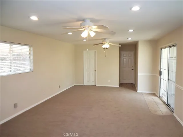 an empty room with chandelier fan and windows