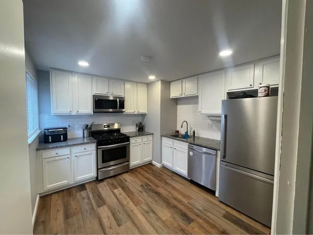 a kitchen with a refrigerator a stove top oven a sink and cabinets