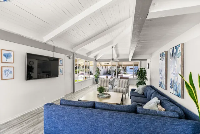 a living room with stainless steel appliances furniture wooden floor and a large window