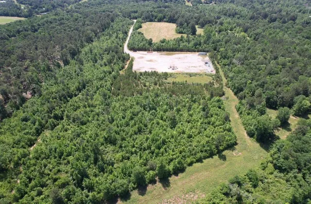 an aerial view of a house with a yard and trees all around