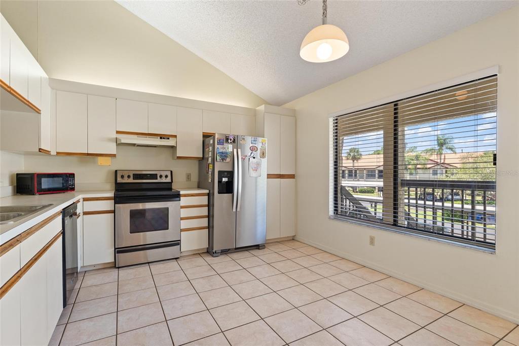 1801 East Lake Road South, Unit 4E Palm Harbor, FL 34685 - Photo 7 of 26 a kitchen with a refrigerator a stove top oven a sink and a window