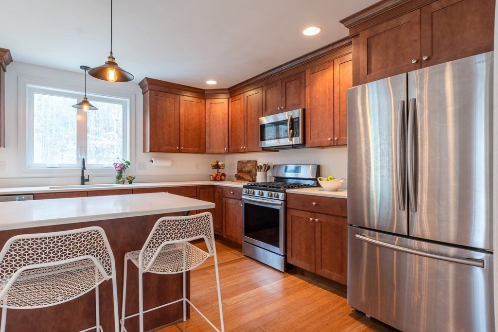 188 South Road Pepperell, MA 01463 - Photo 12 of 41 a kitchen with stainless steel appliances granite countertop a refrigerator a stove a sink dishwasher a dining table and chairs with wooden floor