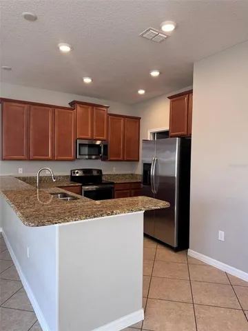 a kitchen with stainless steel appliances granite countertop a refrigerator a sink a stove a microwave and island