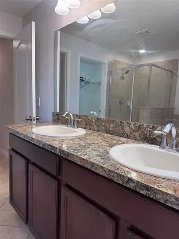 a bathroom with a granite countertop double vanity sinks and a large mirror