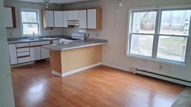 a kitchen with stainless steel appliances granite countertop a refrigerator a sink dishwasher a stove and white countertops with wooden floor