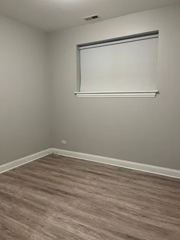 a view of an empty room with wooden floor and mirror