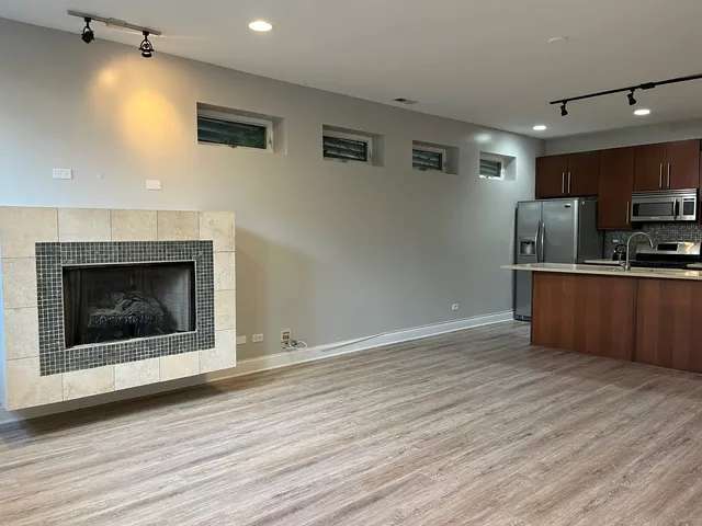 a living room with stainless steel appliances furniture a fireplace and wooden floor