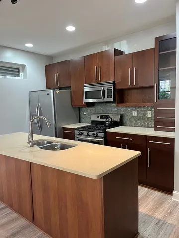 a kitchen with stainless steel appliances wooden cabinets a sink and a refrigerator