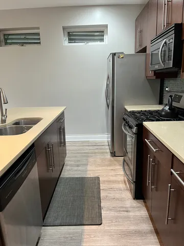 a kitchen with stainless steel appliances granite countertop a refrigerator a stove and a sink with wooden cabinets