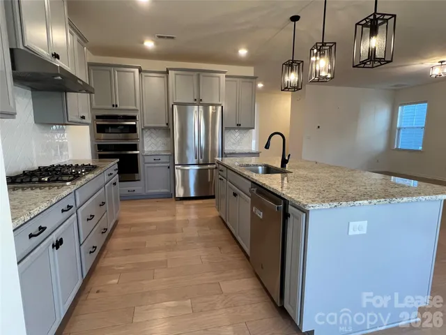 a kitchen with stainless steel appliances granite countertop a sink stove and refrigerator