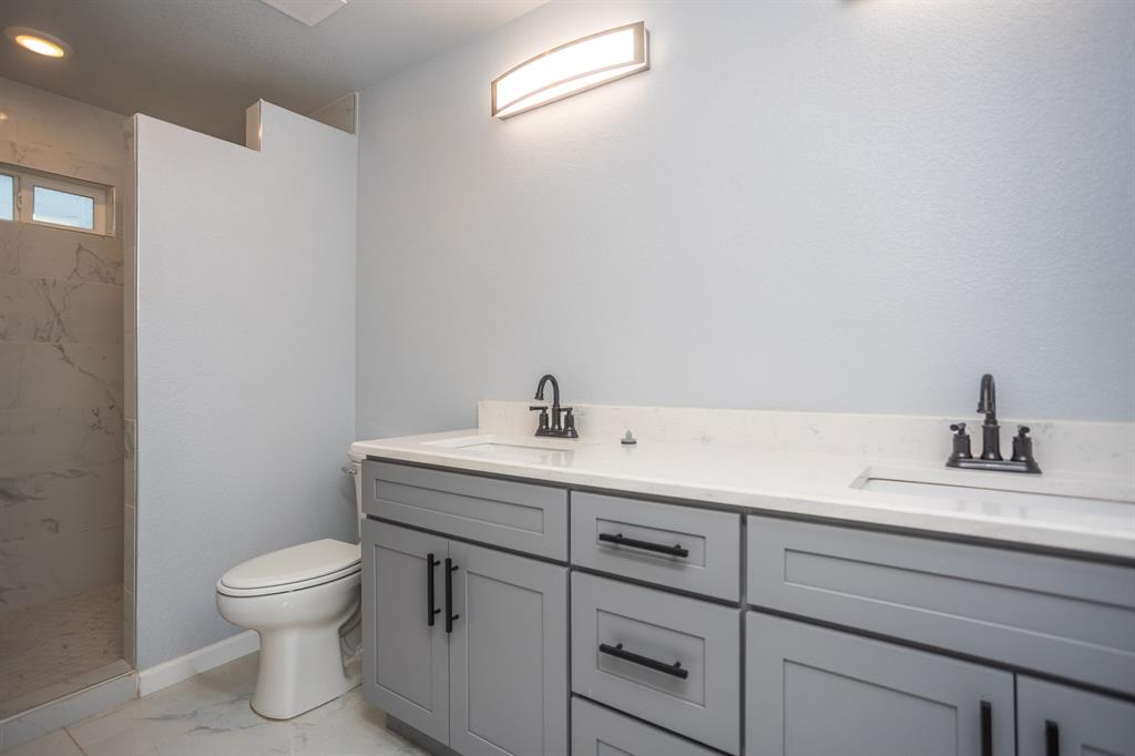 815 Ritchey Street Gainesville, TX 76240 - Photo 8 of 18 a bathroom with a toilet a sink and mirror