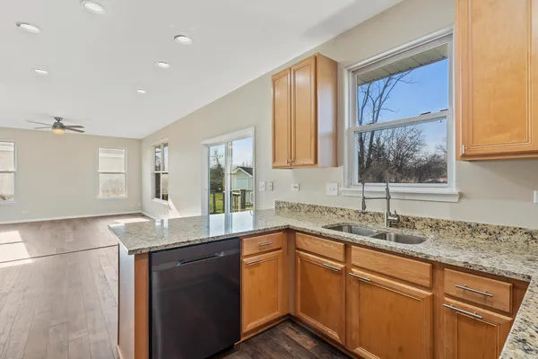 a kitchen with granite countertop kitchen island a sink appliances and a window