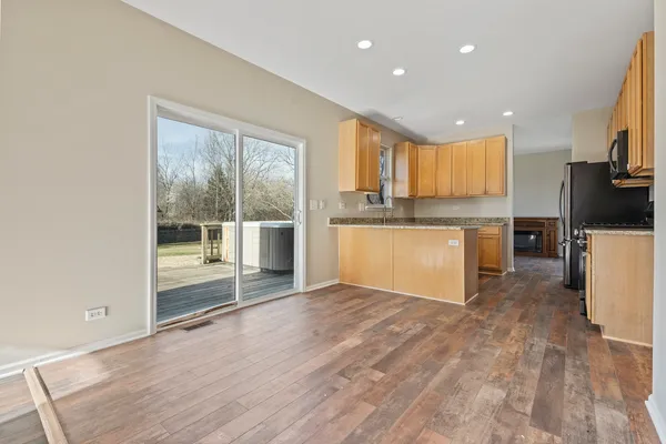 a view of a kitchen with kitchen island a sink wooden floor and a refrigerator