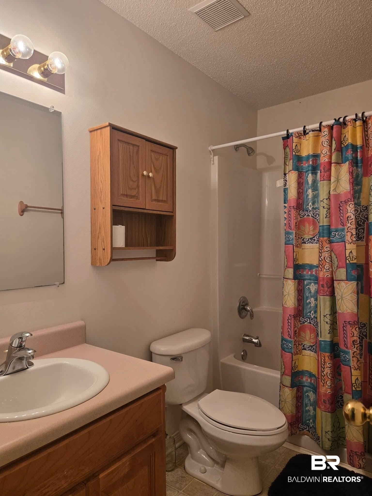 2554 Riverside Drive Mobile, AL 36605 - Photo 9 of 43 Full bathroom featuring shower / bathtub combination with curtain, a textured ceiling, vanity, and light tile patterned flooring