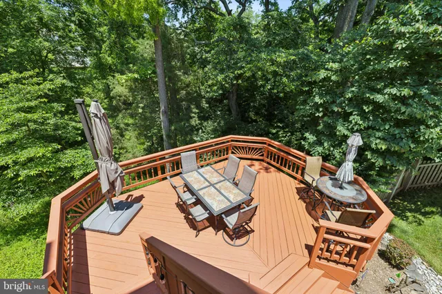 a balcony of a house with wooden floor outdoor seating and yard in the back