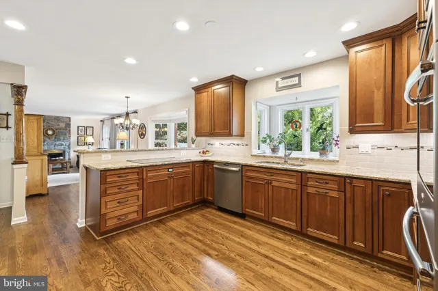 a kitchen with stainless steel appliances granite countertop wooden cabinets a sink a stove a dining table and chairs