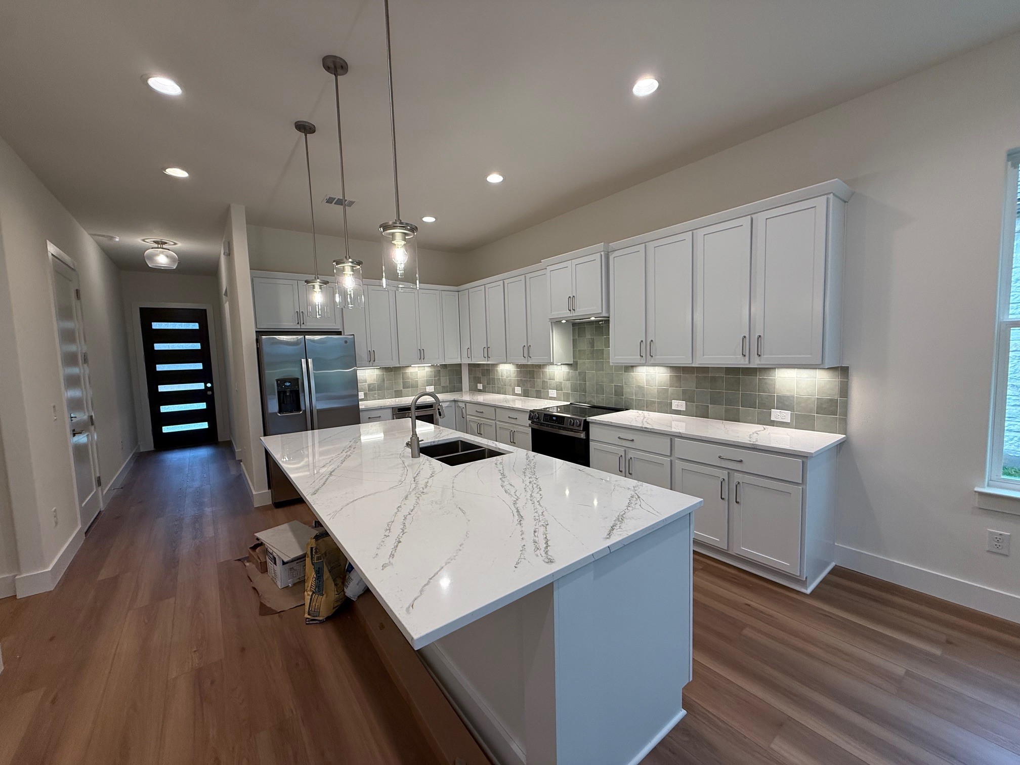 110 Firestone Place Meadowlakes, TX 78654 - Photo 6 of 18 Spacious kitchen featuring an oversized island with quartz countertops, custom cabinetry, a tile backsplash, and stainless steel appliances