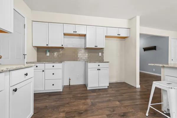a kitchen with white cabinets and wooden floor