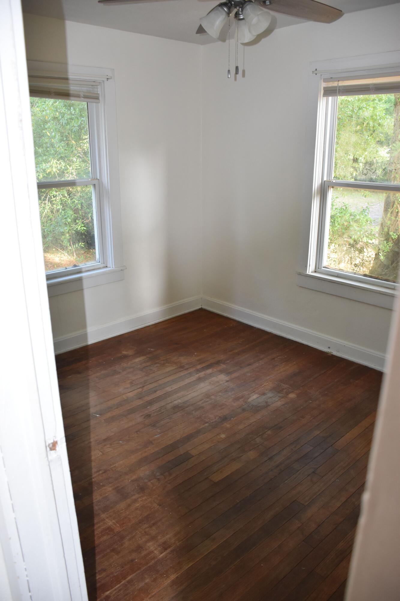 326 Dixie Street Crestview, FL 32536 - Photo 6 of 10 an empty room with wooden floor and windows