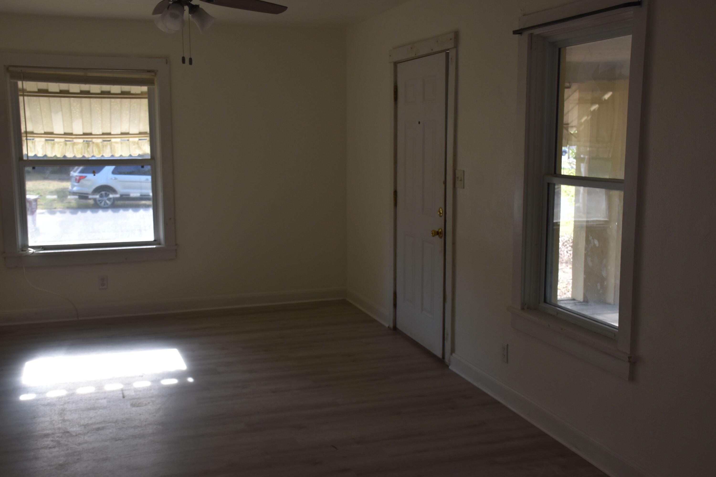 326 Dixie Street Crestview, FL 32536 - Photo 8 of 10 an empty room with wooden floor and windows