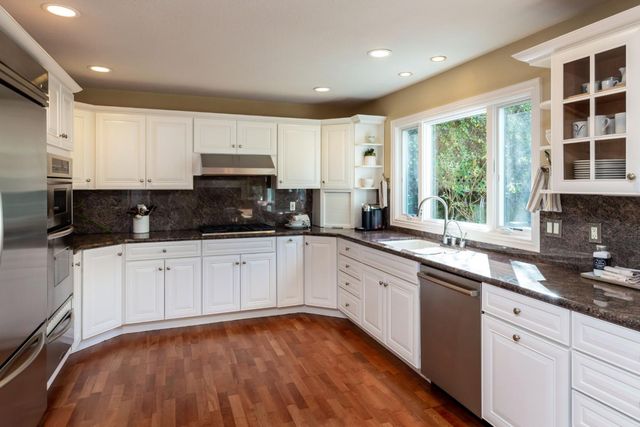 a kitchen with stainless steel appliances granite countertop a stove a sink and white cabinets