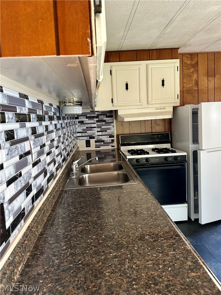 7443 Spillway Road Lisbon, OH 44432 - Photo 10 of 19 Kitchen with white appliances, dark stone counters, white cabinetry, and sink