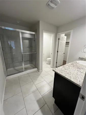 a bathroom with a granite countertop sink a mirror and shower
