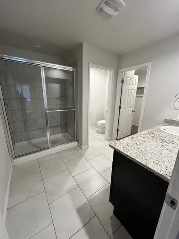 a bathroom with a granite countertop sink a mirror and shower