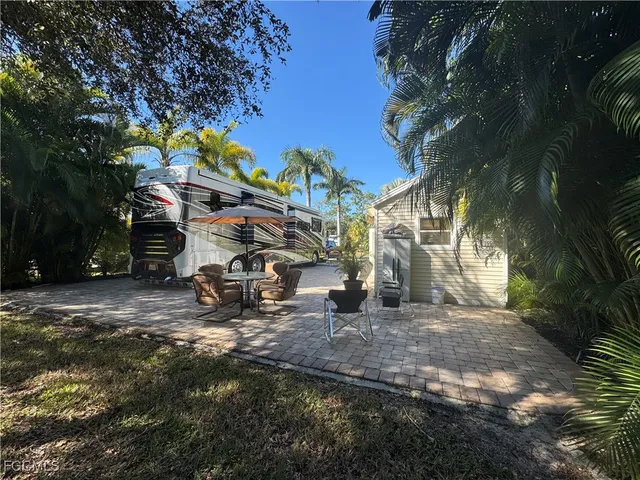 a view of a backyard with table and chairs with a fire pit and a large tree