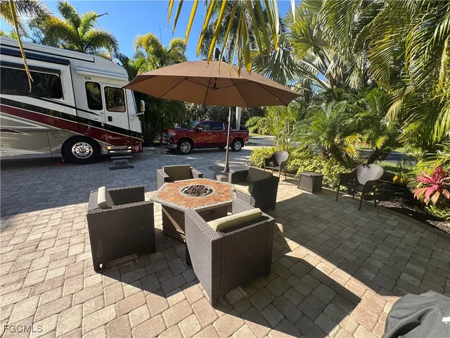 a view of a patio with table and chairs under an umbrella with a barbeque