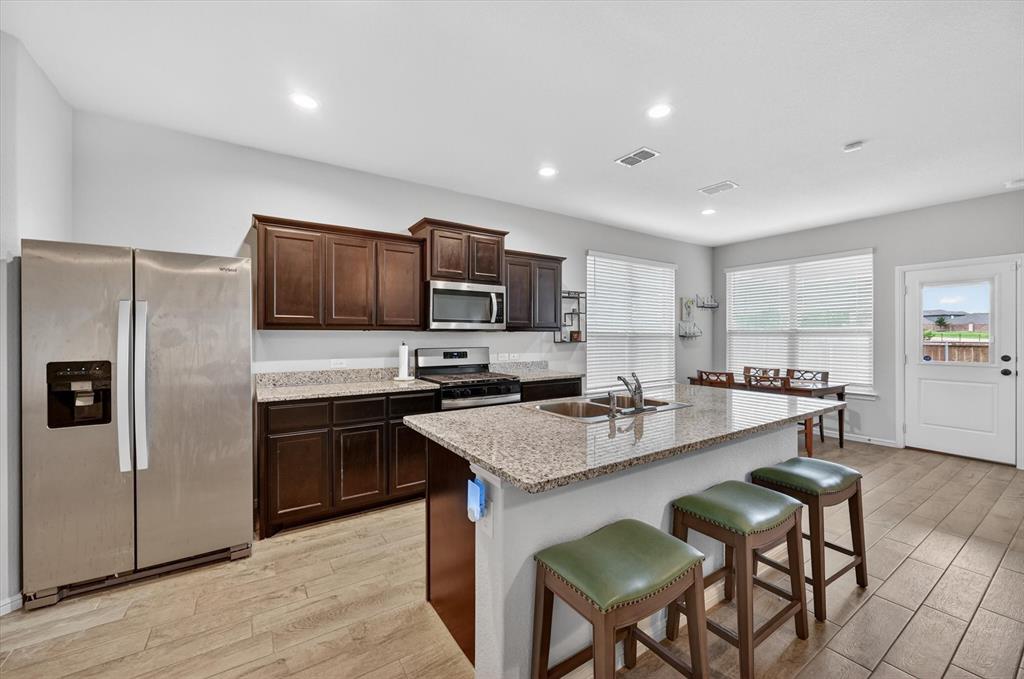 9604 Cherryville Road Fort Worth, TX 76108 - Photo 12 of 40 Kitchen featuring a spacious island with granite countertops, wood-finish tile flooring, recessed lighting, and stainless steel appliances