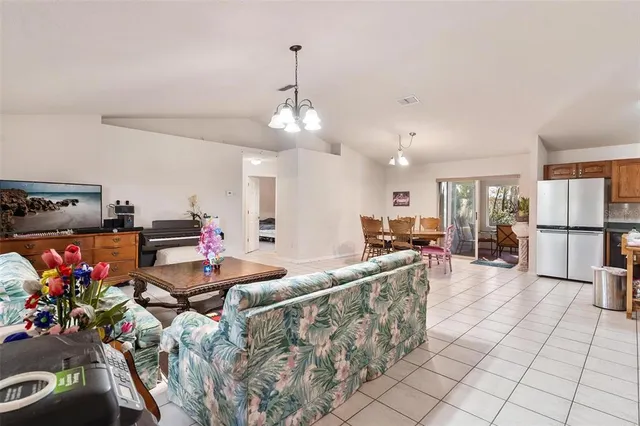 a living room with furniture a chandelier and kitchen view
