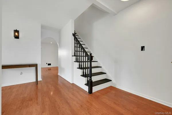 a view of an empty room with wooden floor and stairs