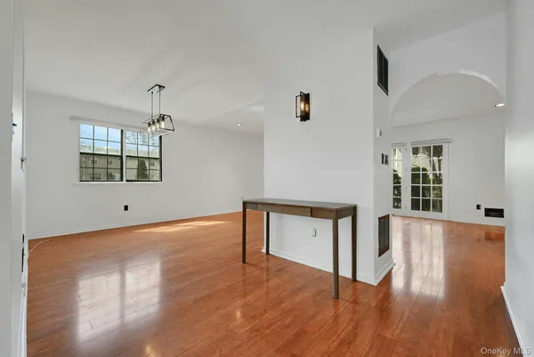 a hallway with wooden floor chandelier and windows
