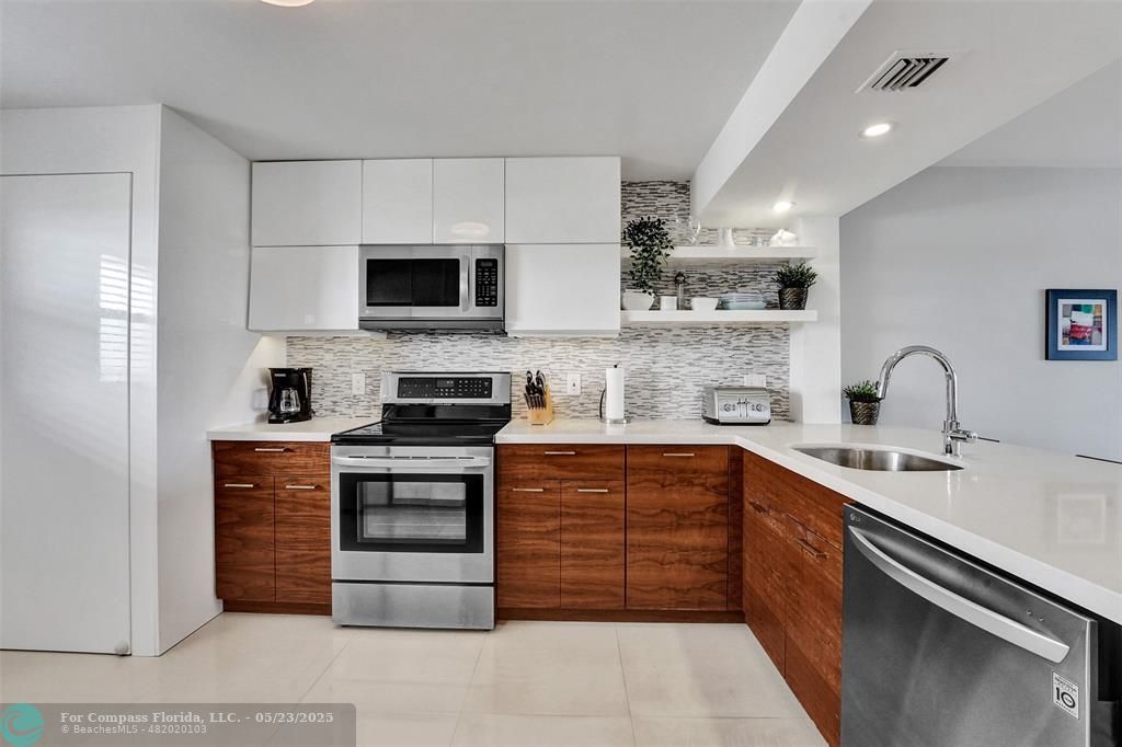 1523 East Hillsboro Boulevard, Unit 1031 Deerfield Beach, FL 33441 - Photo 2 of 78 a kitchen with stainless steel appliances a stove sink and microwave