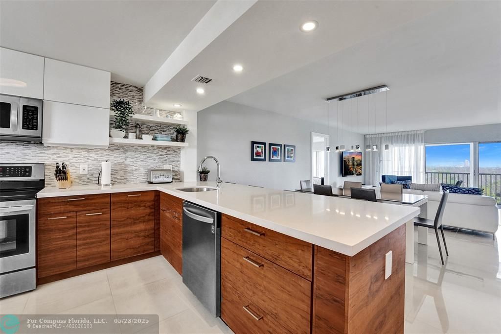 1523 East Hillsboro Boulevard, Unit 1031 Deerfield Beach, FL 33441 - Photo 4 of 78 a kitchen with a sink a stove a center island and cabinets