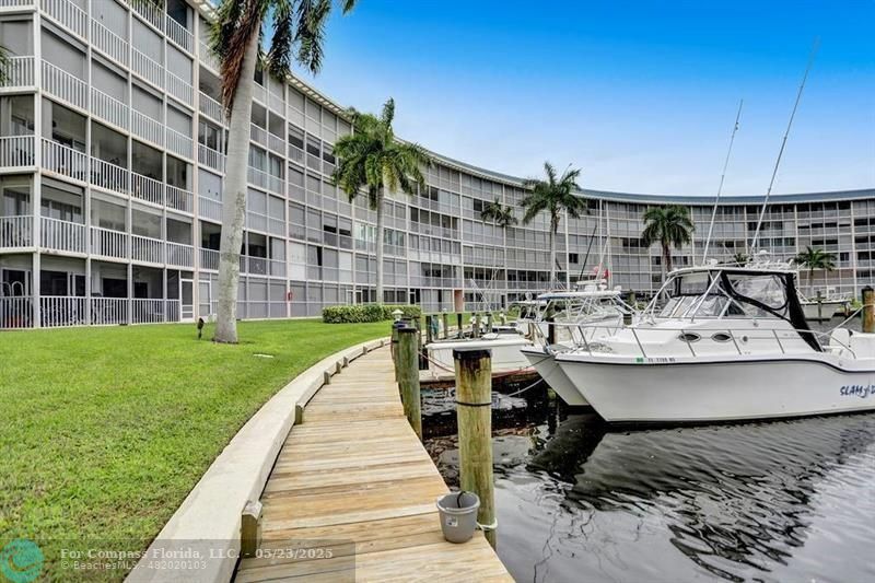 1523 East Hillsboro Boulevard, Unit 1031 Deerfield Beach, FL 33441 - Photo 67 of 78 a view of a patio with table and chairs with wooden floor and fence