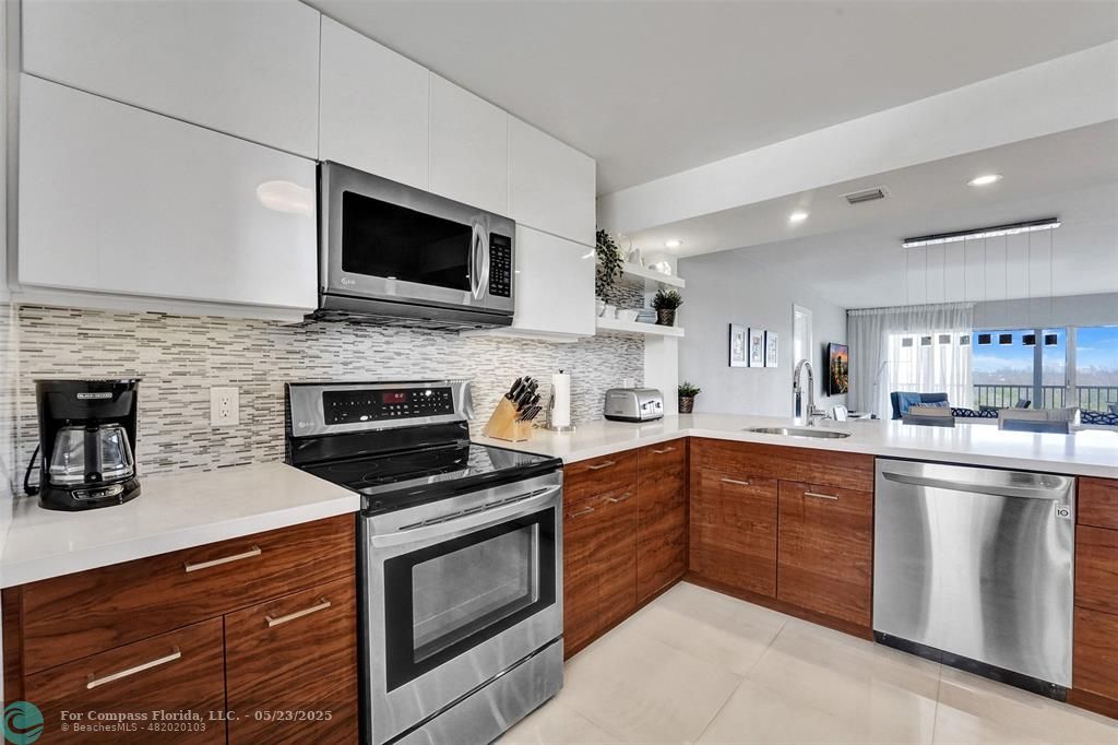 1523 East Hillsboro Boulevard, Unit 1031 Deerfield Beach, FL 33441 - Photo 9 of 78 a kitchen with stainless steel appliances granite countertop a stove top oven a sink and a microwave