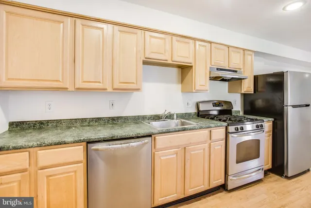 a kitchen with stainless steel appliances granite countertop a stove a sink and a refrigerator
