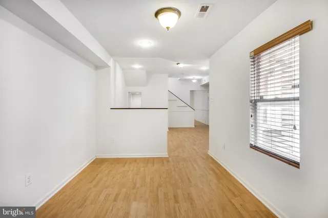 a view of empty room with wooden floor and fan