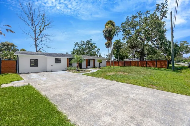 a view of a house with a yard and a large tree