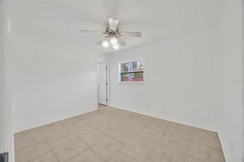 an empty room with a fan & a window