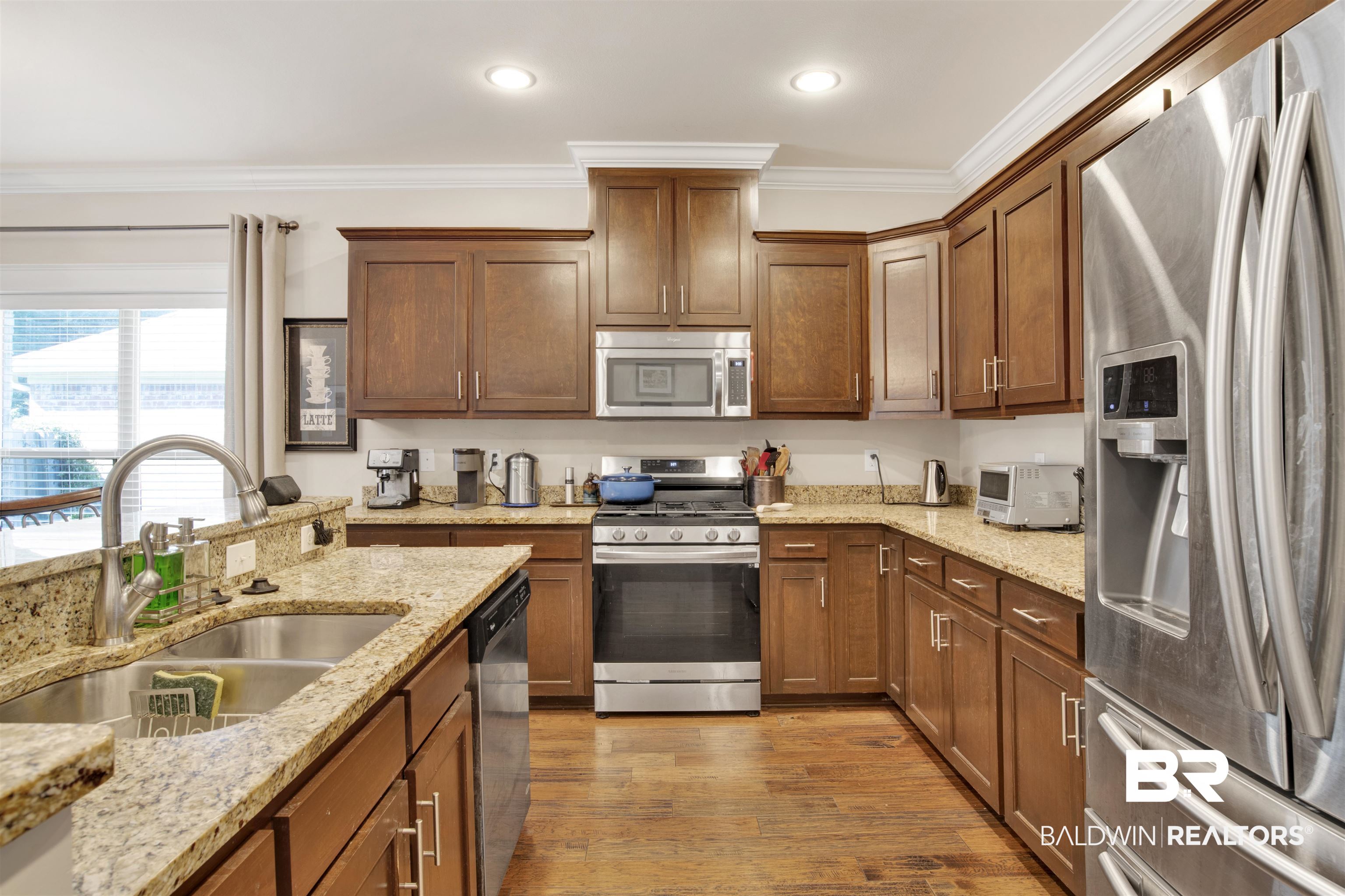 360 Scarlett Avenue Fairhope, AL 36532 - Photo 12 of 34 Kitchen with light stone counters, ornamental molding, sink, stainless steel appliances, and dark hardwood / wood-style floors