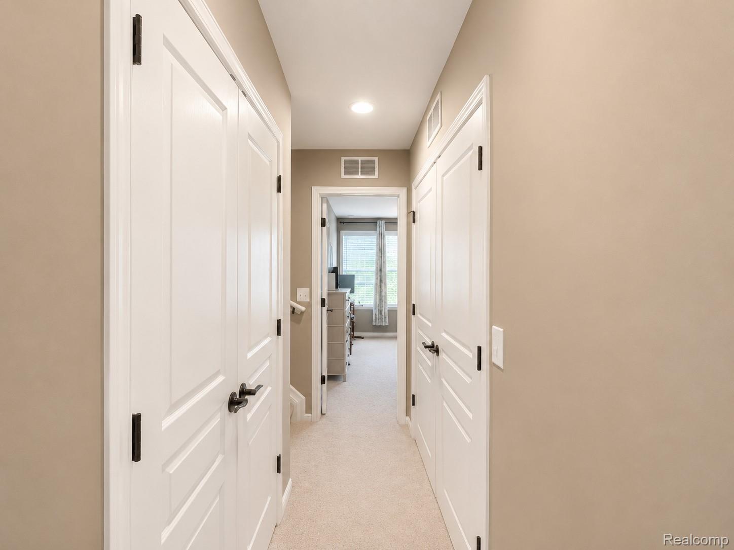 915 Barclay Circle Rochester, MI 48307 - Photo 8 of 14 Hallway featuring neutral wall tones, white paneled doors with matte black hardware, recessed lighting, and carpeted flooring