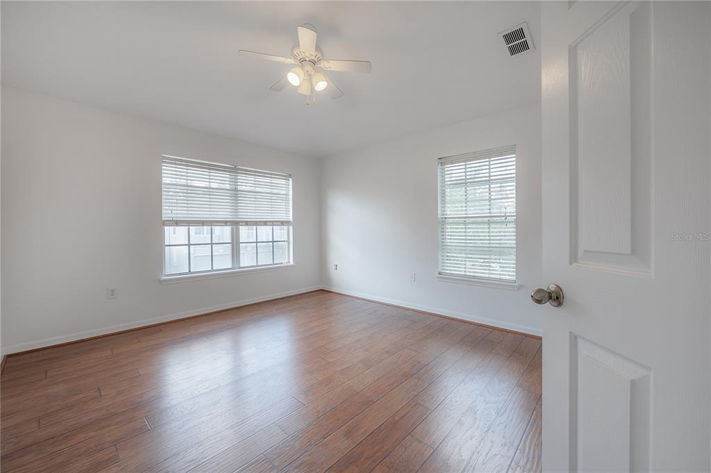 27834 Pleasure Ride Loop Wesley Chapel, FL 33544 - Photo 18 of 25 an empty room with wooden floor chandelier fan and windows