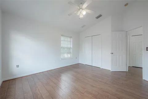 an empty room with wooden floor fan and windows