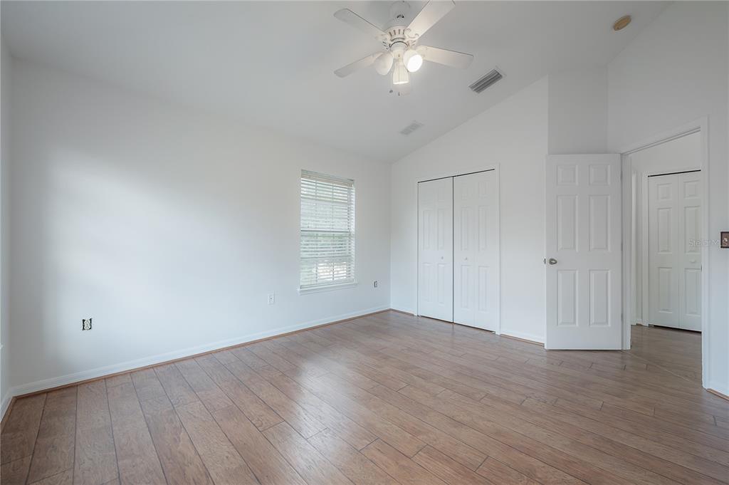 27834 Pleasure Ride Loop Wesley Chapel, FL 33544 - Photo 19 of 25 an empty room with wooden floor fan and windows