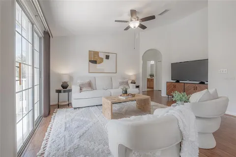 a living room with furniture a ceiling fan and a flat screen tv